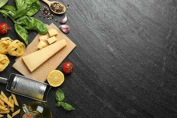 Different types of pasta, spices, garter and products on dark textured table, flat lay. Space for...