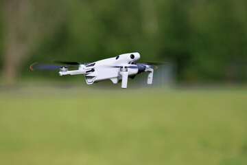 Dron w powietrzu, w locie na tle zieleni. © Stanisław Błachowicz