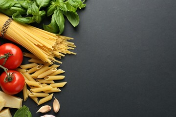 Different types of pasta, spices and products on black background, flat lay. Space for text