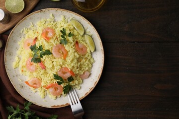 Delicious risotto with shrimps, lime and parsley served on wooden table, flat lay. Space for text
