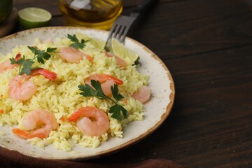 Delicious risotto with shrimps, parsley and lime on wooden table, closeup