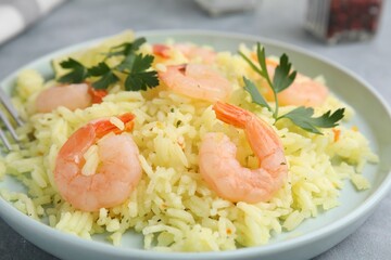 Delicious risotto with shrimps and parsley on table, closeup