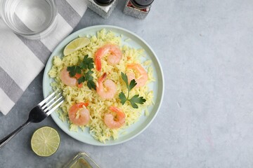 Delicious risotto with shrimps, lime and parsley served on light grey table, flat lay. Space for...