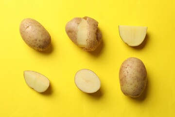 Fresh raw potatoes on yellow background, flat lay