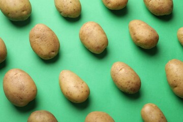 Fresh raw potatoes on green background, flat lay
