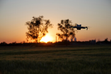 Dron w powietrzu nad polami, w tle zachód słońca.