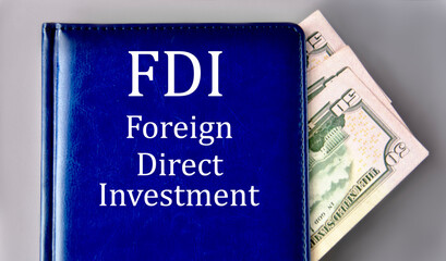 FDI - acronym on a blue book on a gray background with banknotes