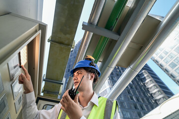 Industrial engineer adjusting pipeline valve with radio communication on construction site....