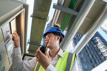 Industrial engineer adjusting pipeline valve with radio communication on construction site....