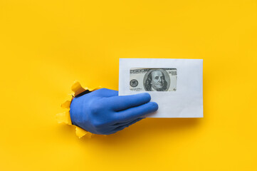 The right male hand in a blue fabric work glove holds an envelope with dollar bills (money). Torn...
