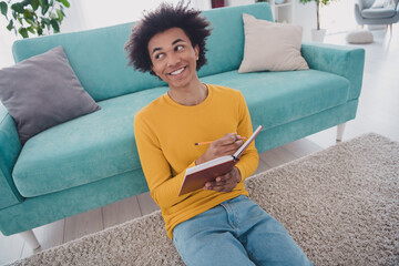 Photo of nice young man sit floor hold book pencil wear yellow pullover white interior apartment...