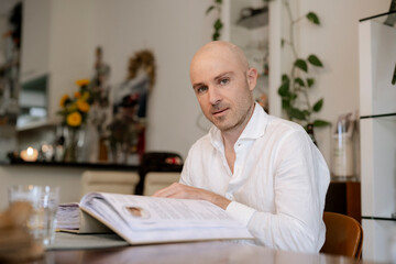 Mann sitzt an einem Tisch und blättert in einem Album