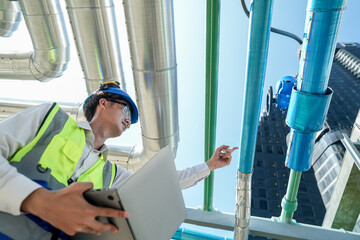 Industrial engineer adjusting pipeline valve with radio communication on construction site....