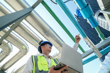 Industrial engineer adjusting pipeline valve with radio communication on construction site....