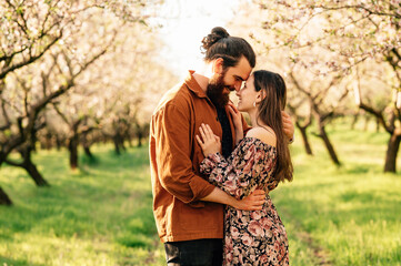 Young handsome man is holding tight his beloved woman in an almond orchard.