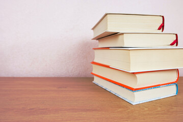Stack of many old books on shelf in book store or library room with white wall background.