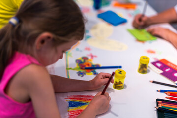 Child girl draws with colored pencils