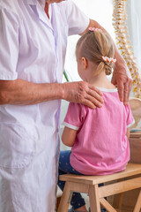 male Orthopedist doctor examining child's back in clinic, physician checks girl's spinal alignment,...