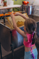 Girl Use beekeeping tools to open wax cells filled with the finished product.