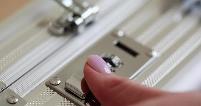 Woman hand presses key to open case with combination lock in light premise. Female person uses briefcase with improved security device slow motion