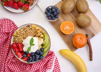 Granola with strawberries, kiwi, banana and blueberries in a round plate on a black table. Healthy and tasty food