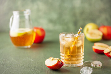 Apple juice and sparkling water in glass. Apfelschorle German drink. Apple fruit, ice and leaves in...