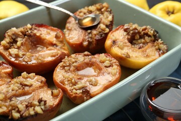 Tasty baked quinces with nuts and honey in dish on grid, closeup