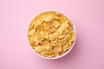 Breakfast cereal. Tasty corn flakes in bowl on pink table, top view