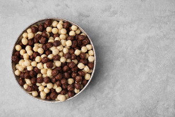 Tasty cereal balls in bowl on grey table, top view. Space for text