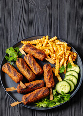 minced beef skewers with potato fries on plate