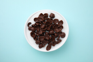 Breakfast cereal. Chocolate corn flakes and milk in bowl on turquoise background, top view