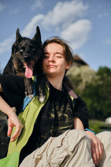 Young woman with black mix breed dog sits and poses together at sunny spring morning. A dog with...