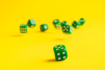 Many green game dices falling on yellow background