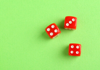 Three red game dices on green background, flat lay
