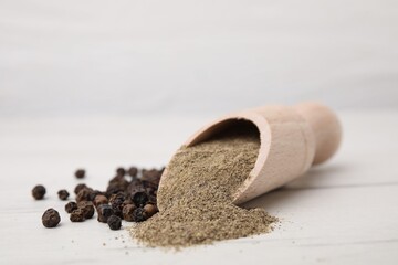 Aromatic spice. Ground pepper in scoop and black peppercorns on white wooden table, closeup