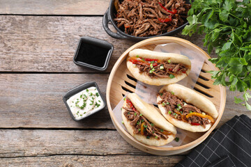 Delicious gua bao in bamboo steamer on wooden table, flat lay. Space for text