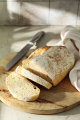 Naklejka premium Freshly baked sourdough bread and knife on light table