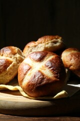Tasty hot cross buns on wooden table against dark background, closeup