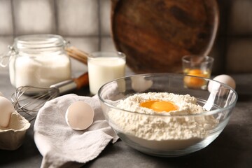 Making dough. Flour with egg yolk in bowl on grey table, closeup