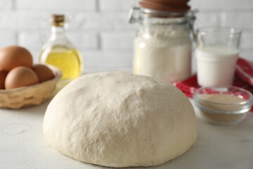 Raw dough and ingredients on white table
