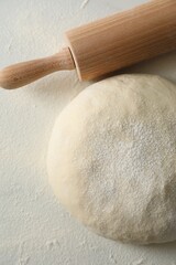 Raw dough and rolling pin on table, above view