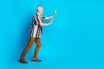Photo of funny nice senior man wear striped stylish clothes push empty space isolated on blue color background
