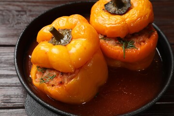 Tasty stuffed peppers in pan on wooden table, closeup