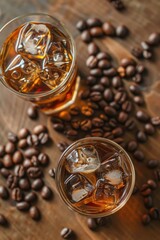 Two glasses of iced coffee with ice cubes and coffee beans on a wooden table. Scene is relaxed and casual