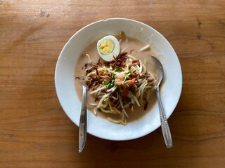 Celor noodles typical of South Sumatra, Indonesia, on a white plate on a wooden table with natural lighting