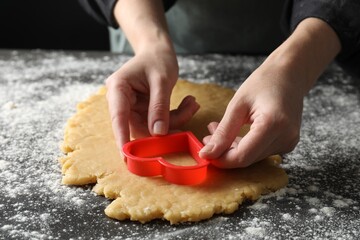 Shortcrust pastry. Woman making cookie with cutter at grey table, closeup