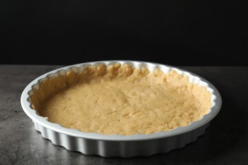 Making shortcrust pastry. Raw dough in baking dish on grey table