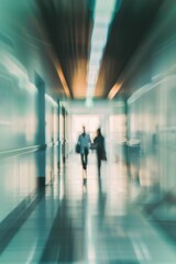 A blurry image of two people walking down a hallway. The hallway is long and narrow, with a bright light shining down on the people. The people are carrying bags, one of which is a handbag