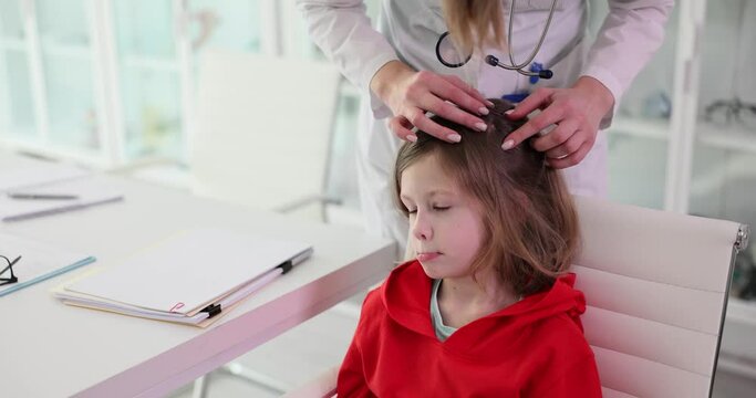 Woman doctor looks for insects in hair of girl patient in clinic office. Specialist in uniform does regular checkup of health and body of calm schoolgirl slow motion