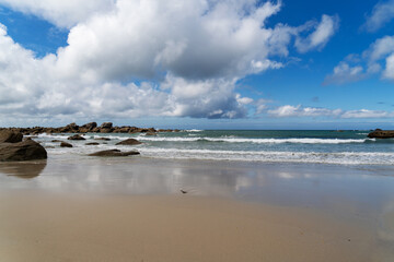 Les reflets des nuages sur les sables mouillés d'une plage bretonne, une vue paisible sur l'Atlantique.